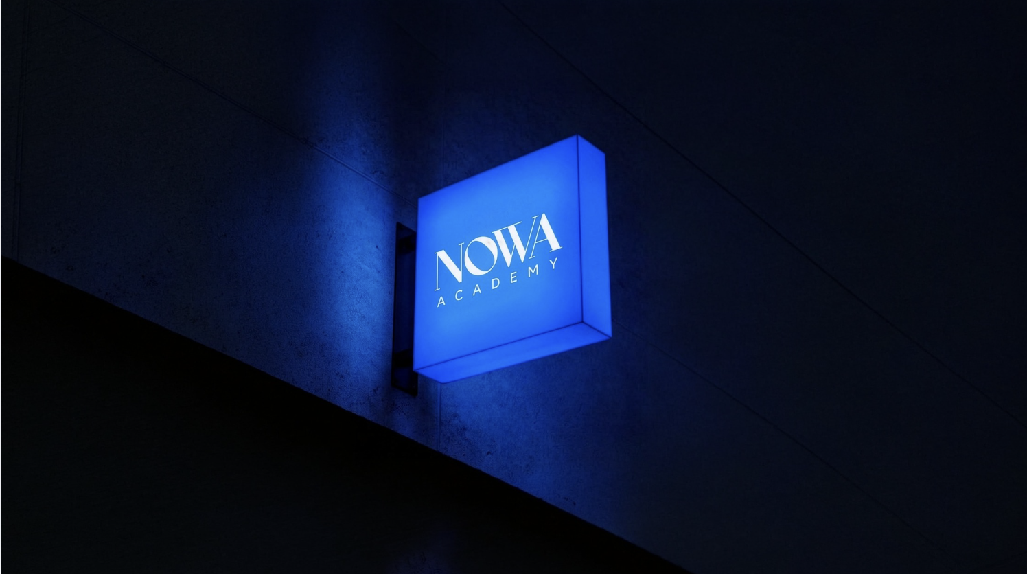 Placa iluminada da NOWA Academy à noite
